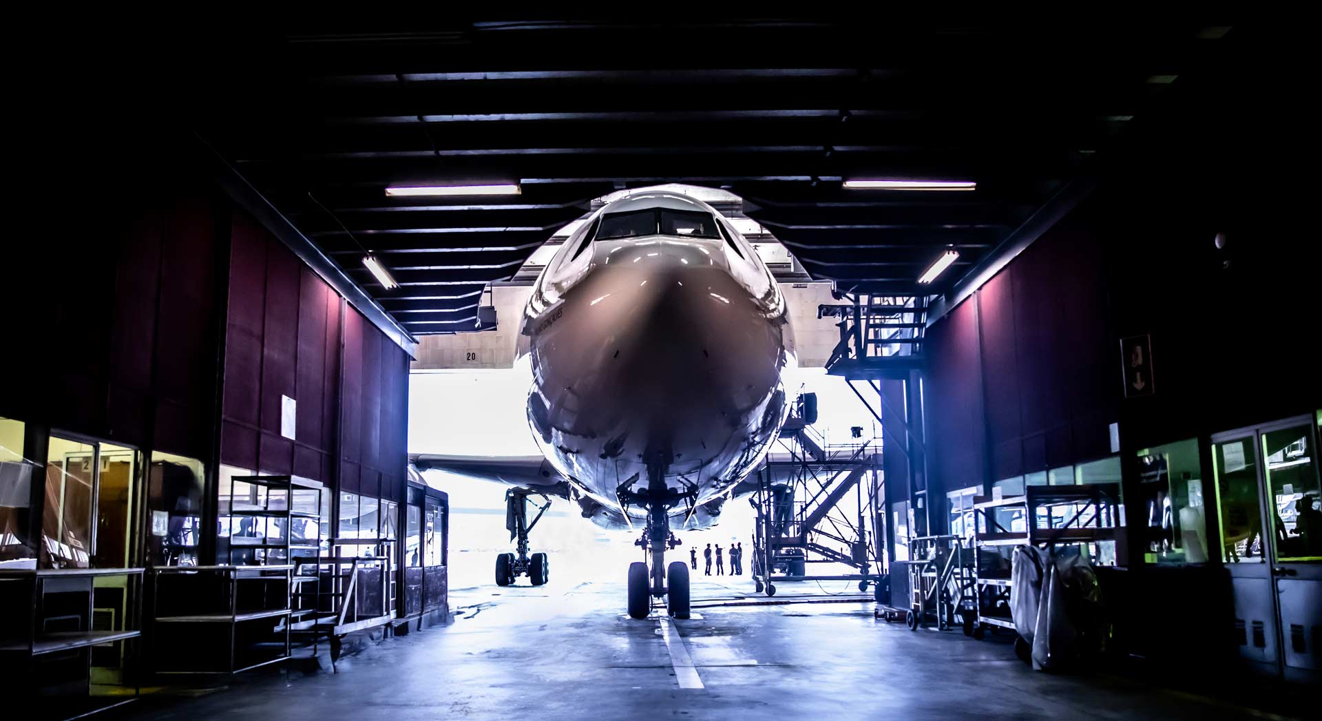 Front view of a commercial airplane inside a large maintenance hangar.