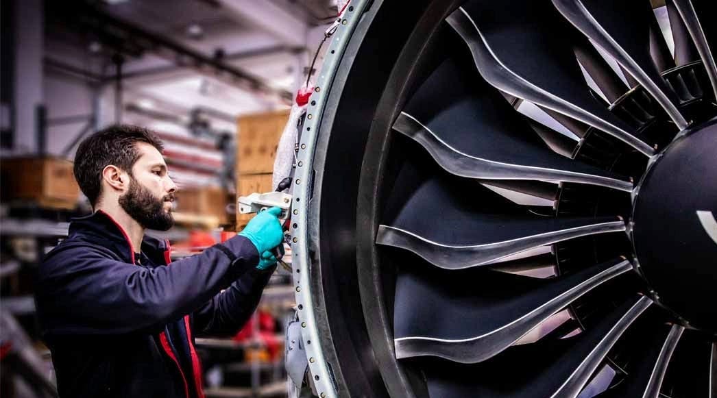 TAP Maintenance technician working on a large aircraft engine, specifically on the fan section of a turbofan jet engine.