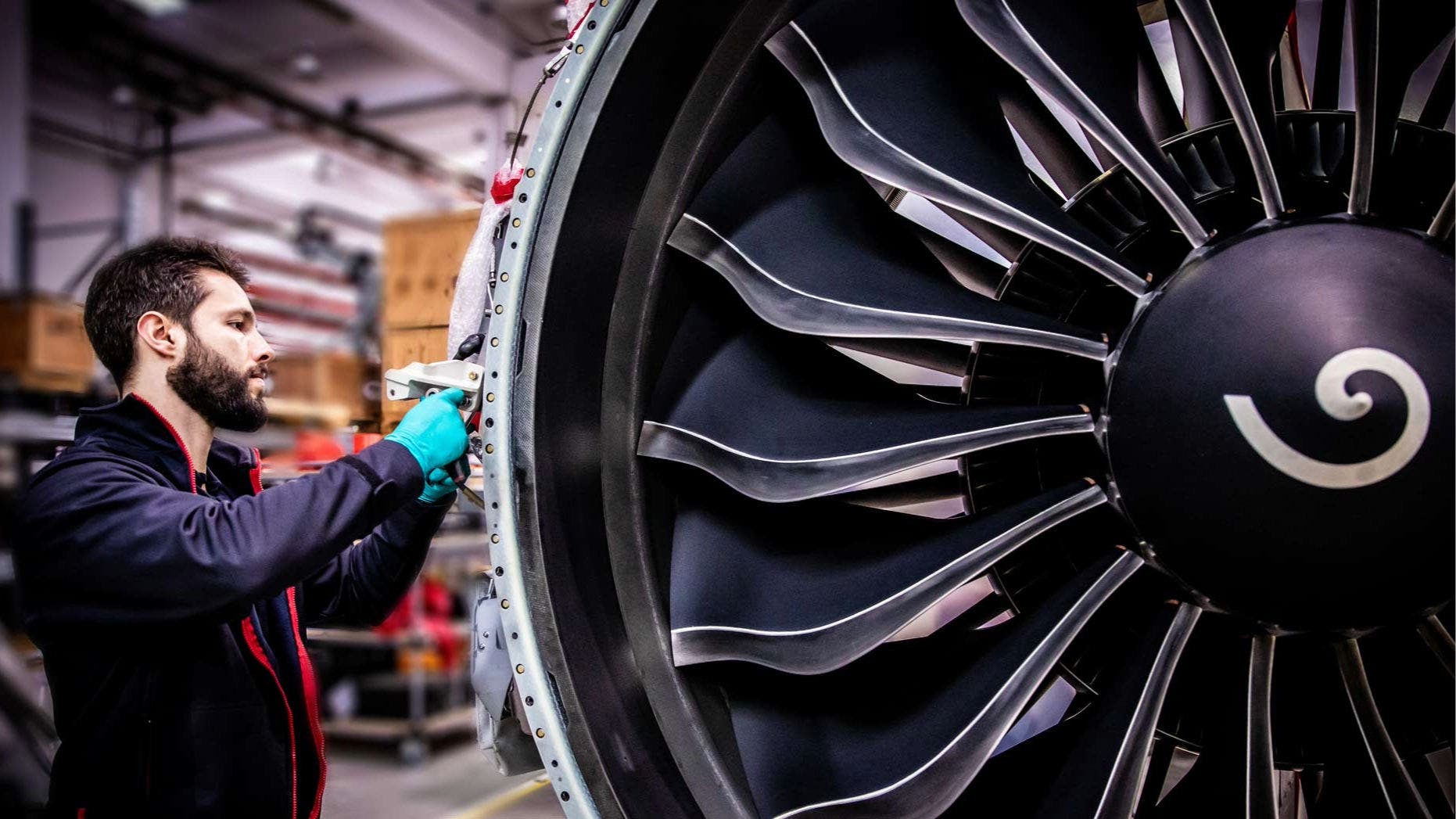 TAP Maintenance technician working on a large aircraft engine, specifically on the fan section of a turbofan jet engine.