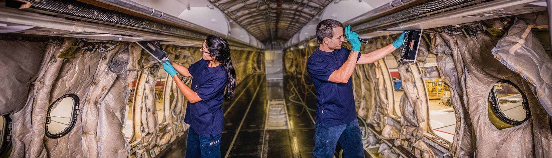 Two TAP Maintenance technicians inspecting the interior structure of an airplane fuselage.